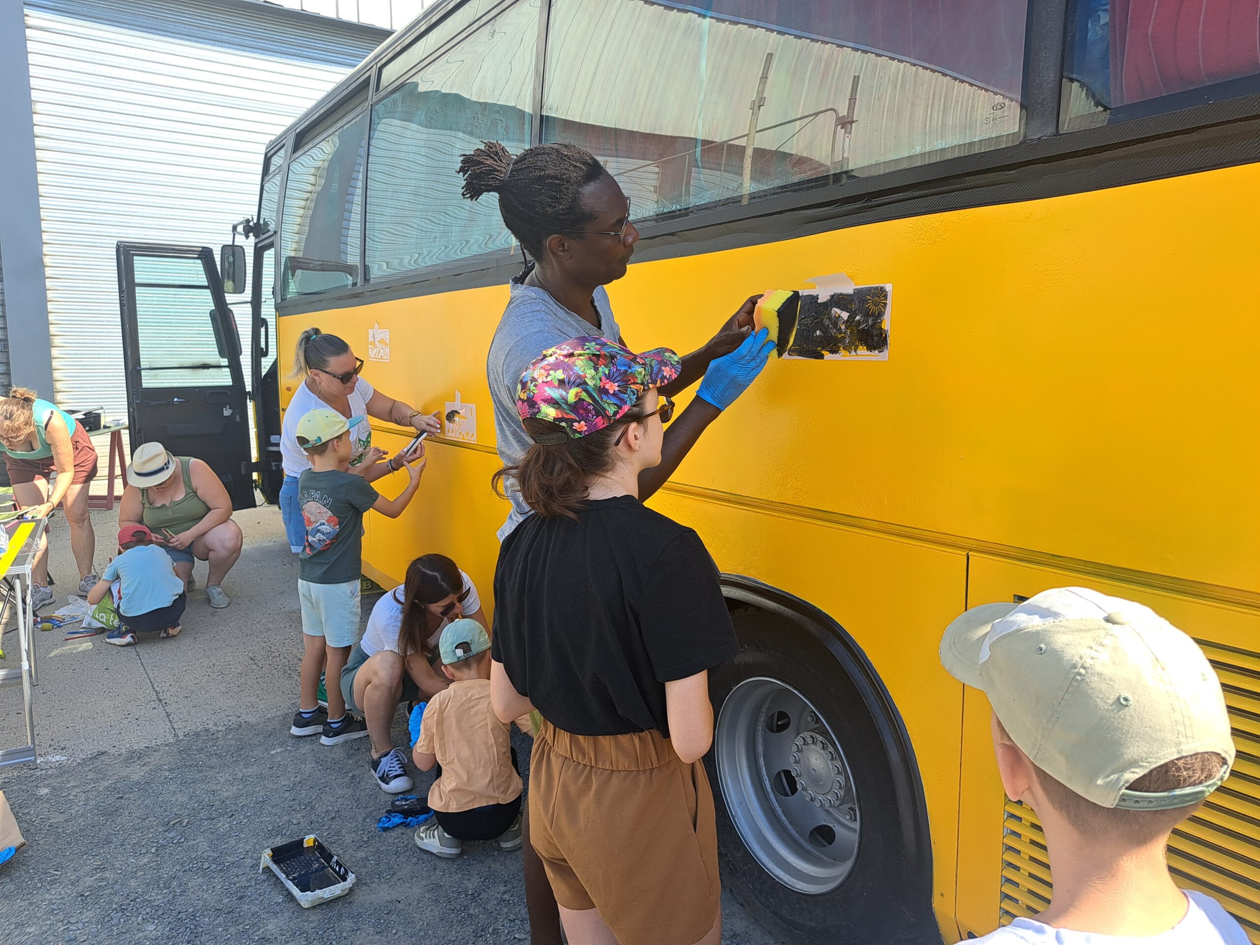 Groupe d’enfants et de bénévoles peignant le bus