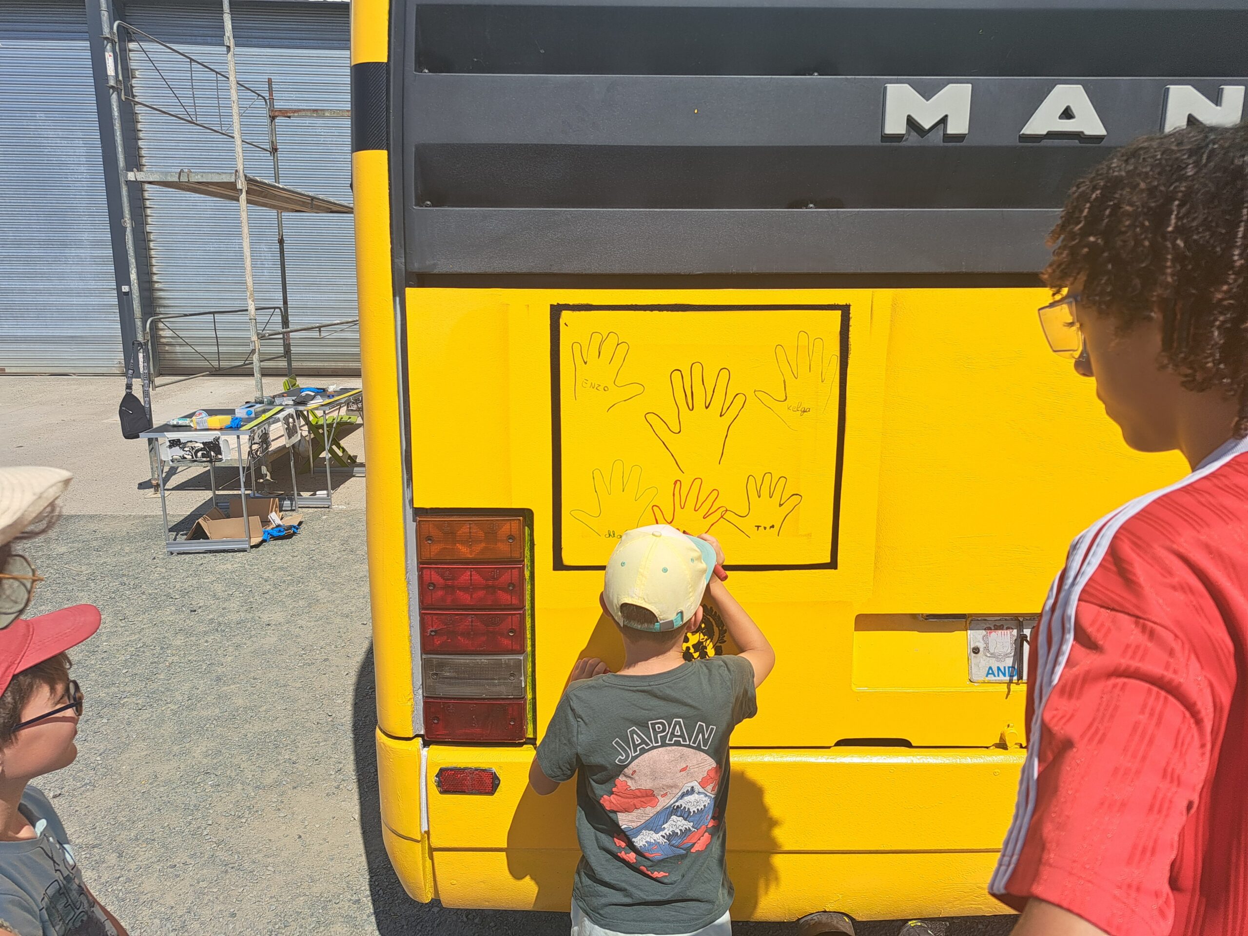 Enfant décorant l’arrière du bus solidaire