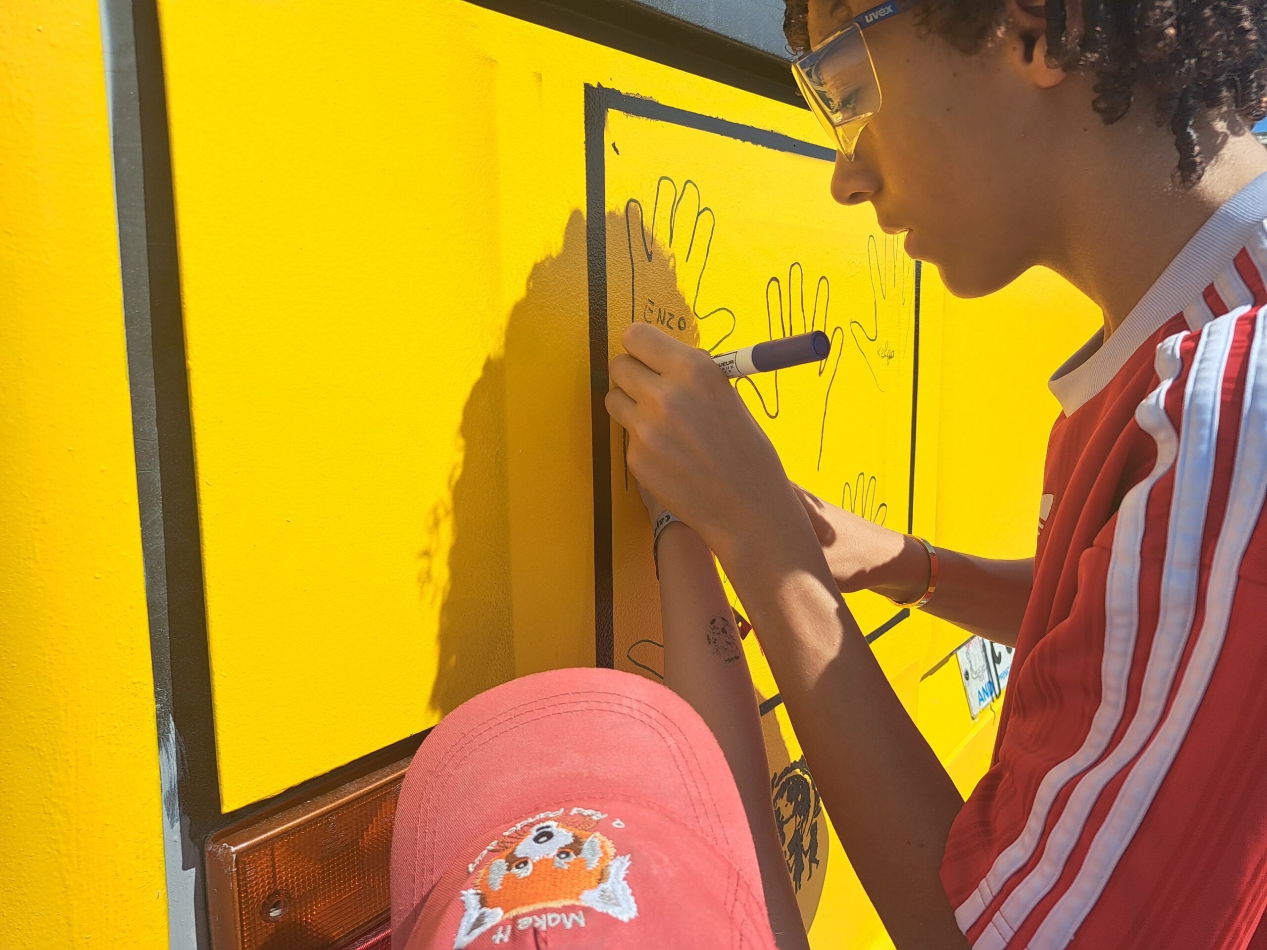 Un jeune participant ajoute son dessin au bus